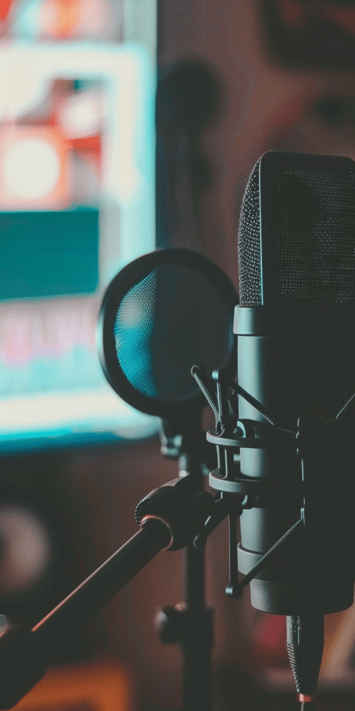 Nahaufnahme eines Mikrofons und Popfilters in einem Tonstudio mit unscharfem Hintergrund.