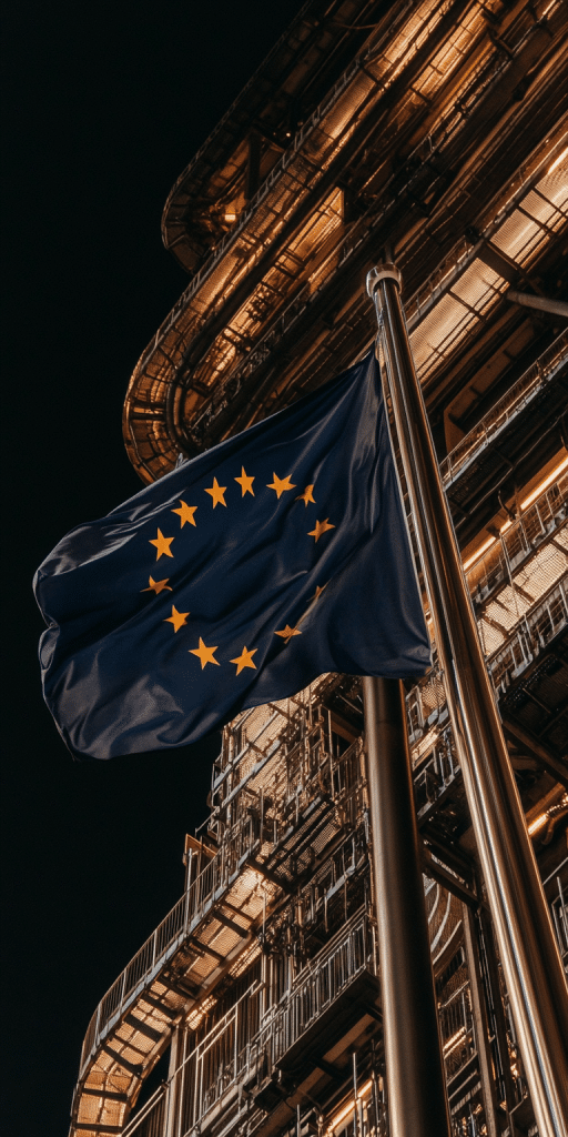 Europäische Flagge weht bei Nacht vor einem futuristischen, beleuchteten Gebäude